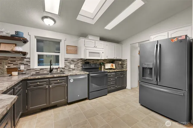 a kitchen with stainless steel appliances granite countertop a refrigerator a sink dishwasher a stove and a refrigerator