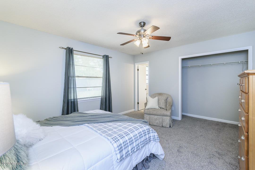 2526 Wattle Tree Road West Jacksonville, FL 32246 - Photo 13 of 19 a bedroom with a bed and a chandelier