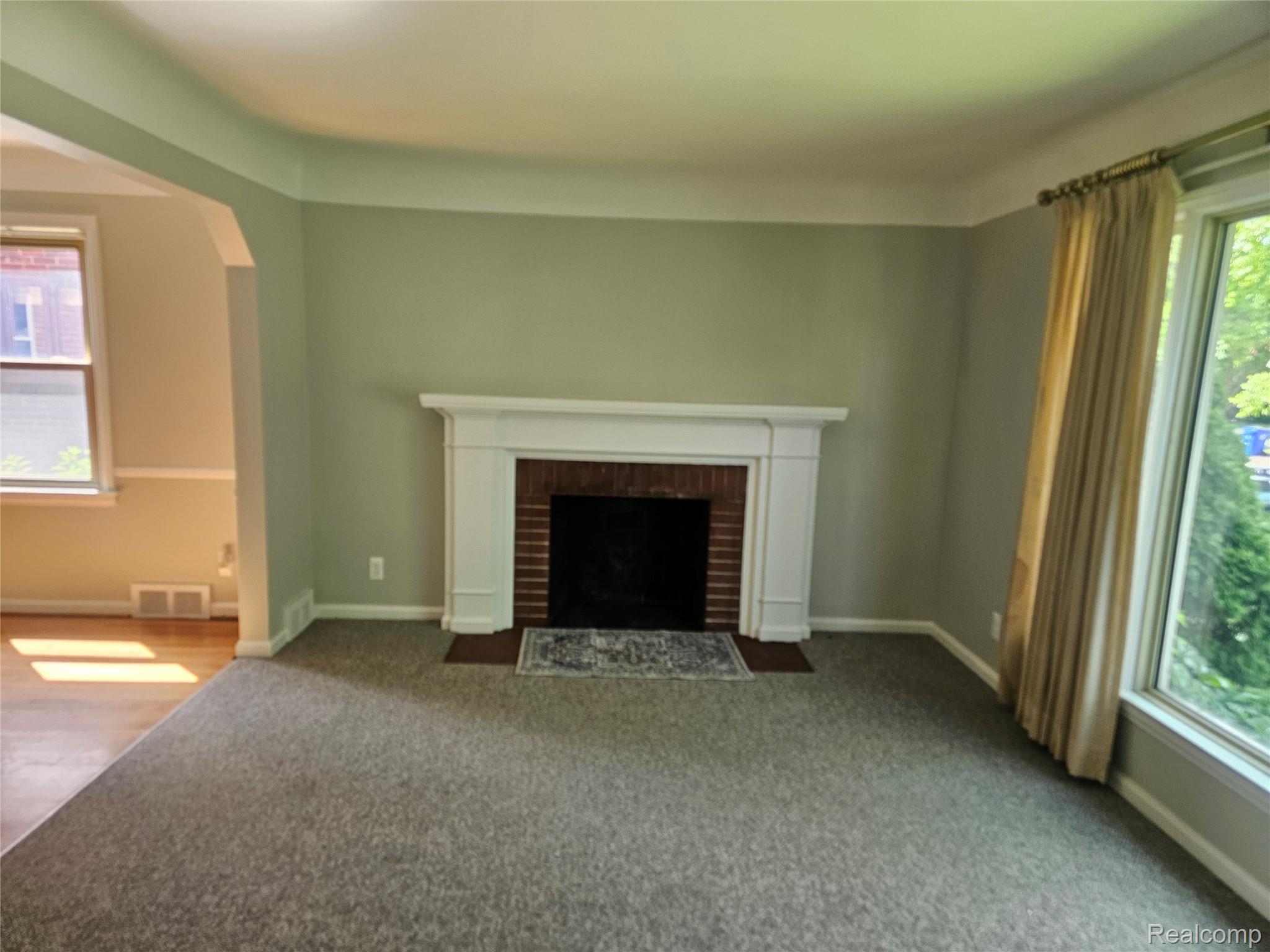 5240 Harvard Road Detroit, MI 48224 - Photo 5 of 18 Living room featuring a brick fireplace with a white mantel, light grey carpeting, and a large window