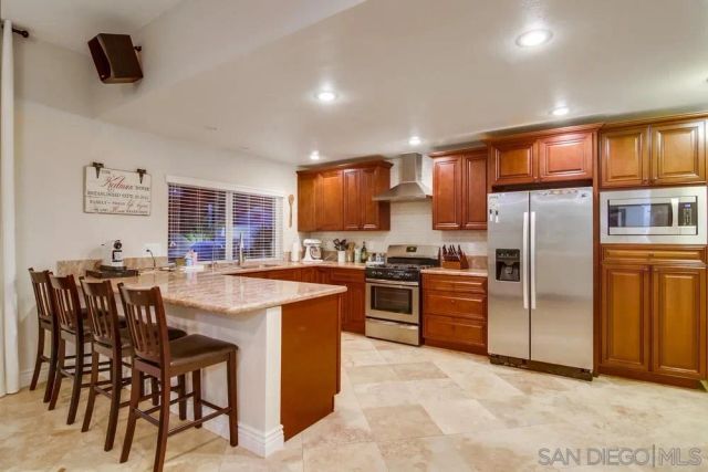 a kitchen with stainless steel appliances granite countertop a stove a refrigerator a oven a sink a dining table and chairs with wooden floor