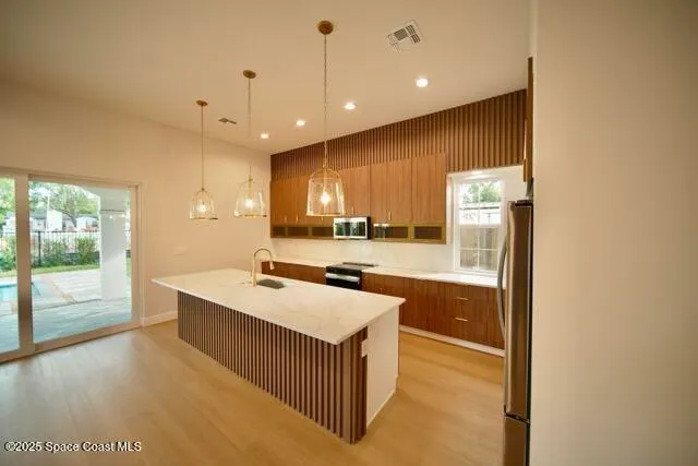 a kitchen with stainless steel appliances a sink a stove top oven a counter space and cabinets