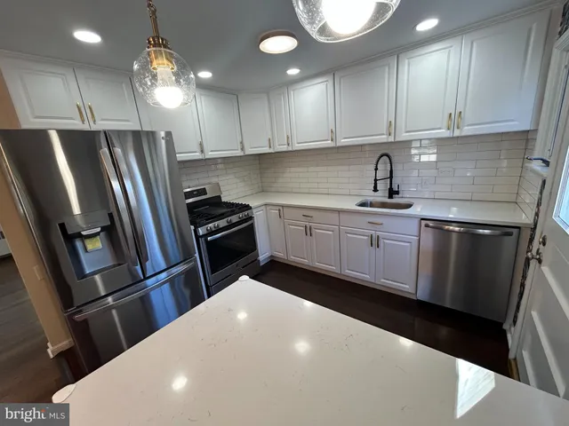 a kitchen with granite countertop a refrigerator sink and cabinets
