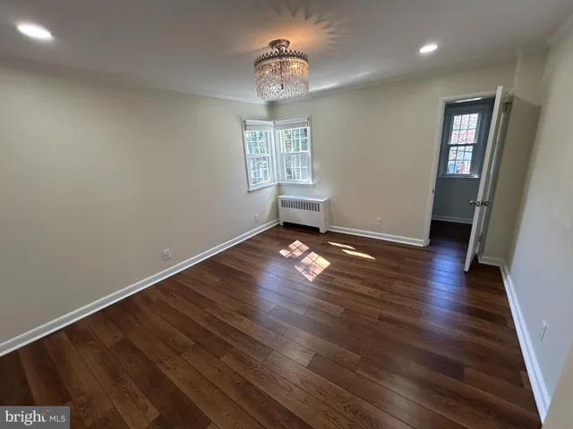 an empty room with wooden floor chandelier fan and windows