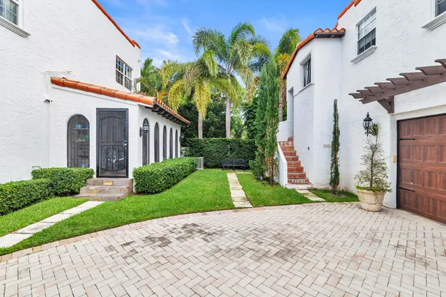 a front view of a house with a yard and potted plants