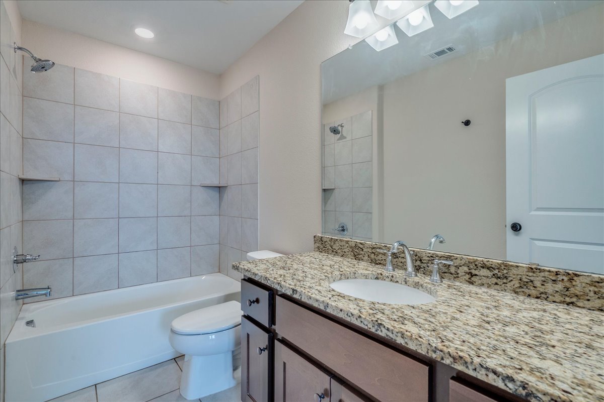 1092 Engelke Road Niederwald, TX 78640 - Photo 13 of 24 a bathroom with a granite countertop bathtub sink vanity mirror and toilet