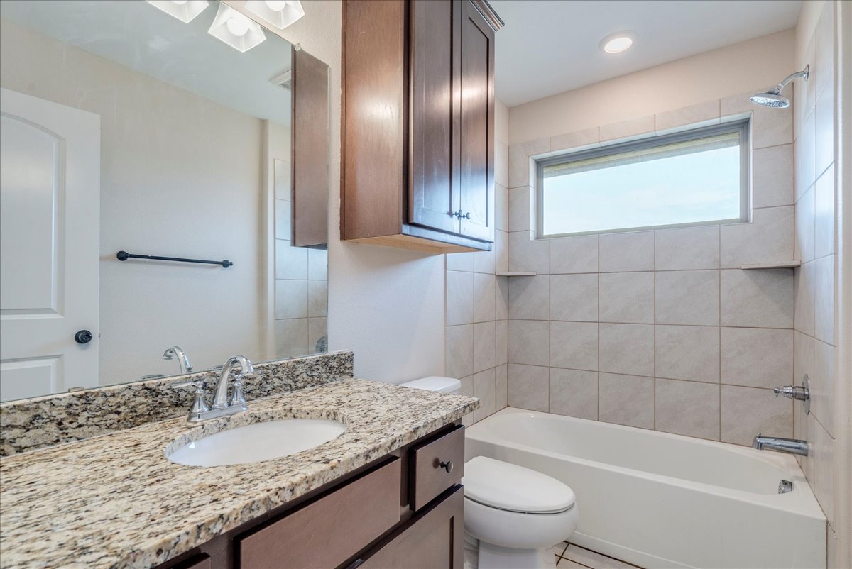1092 Engelke Road Niederwald, TX 78640 - Photo 19 of 24 a bathroom with a granite countertop sink toilet and shower