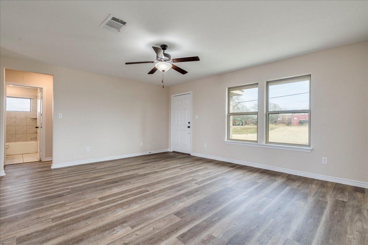 1092 Engelke Road Niederwald, TX 78640 - Photo 6 of 24 an empty room with wooden floor chandelier fan and windows