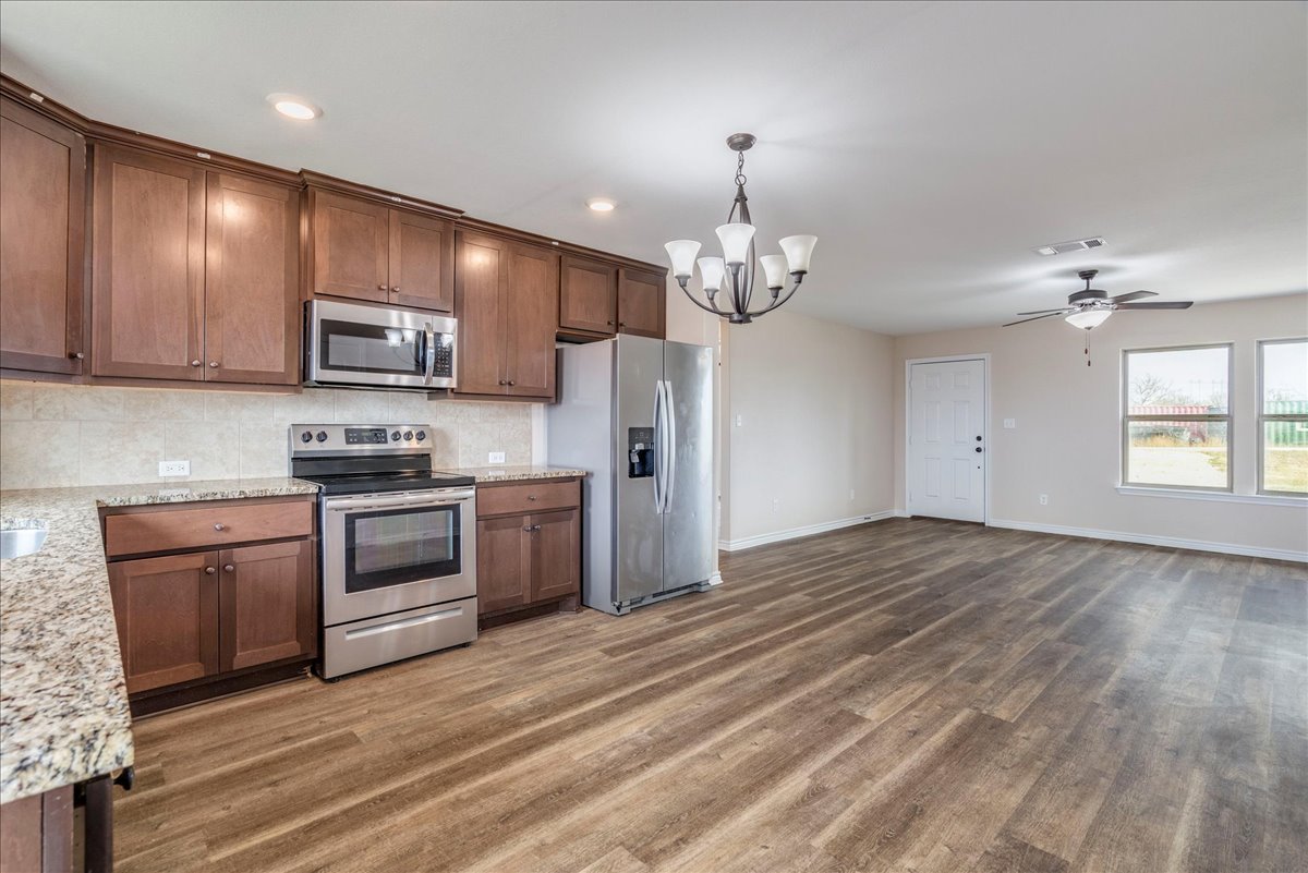 1092 Engelke Road Niederwald, TX 78640 - Photo 10 of 24 a kitchen with stainless steel appliances granite countertop a stove refrigerator and microwave