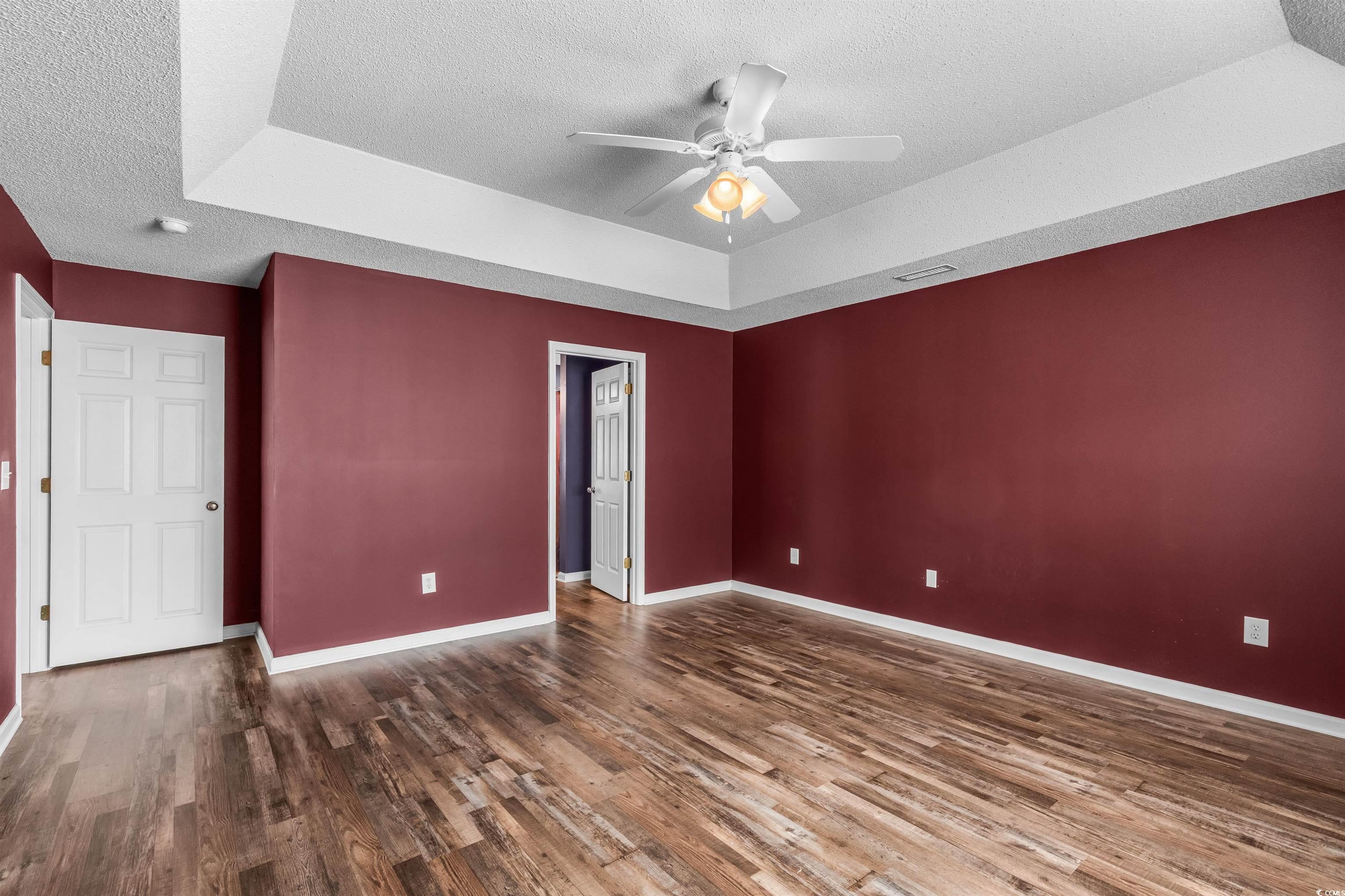 5029 Capulet Circle Myrtle Beach, SC 29588 - Photo 18 of 22 Unfurnished bedroom with a textured ceiling, ceiling fan, wood finished floors, and a tray ceiling