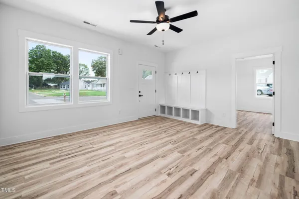 a large white kitchen with kitchen island a stove a sink dishwasher and a fireplace with wooden floor