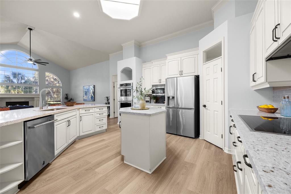 4606 Southwest 97th Terrace Gainesville, FL 32608 - Photo 16 of 68 a kitchen with a refrigerator a sink dishwasher a stove and white cabinets with wooden floor
