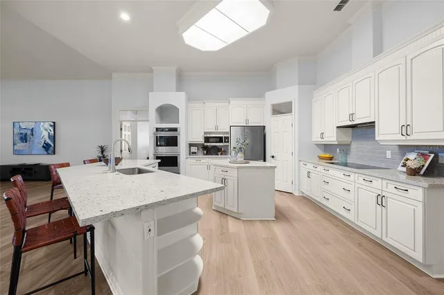 a kitchen with stainless steel appliances kitchen island granite countertop a dining table chairs and view living room