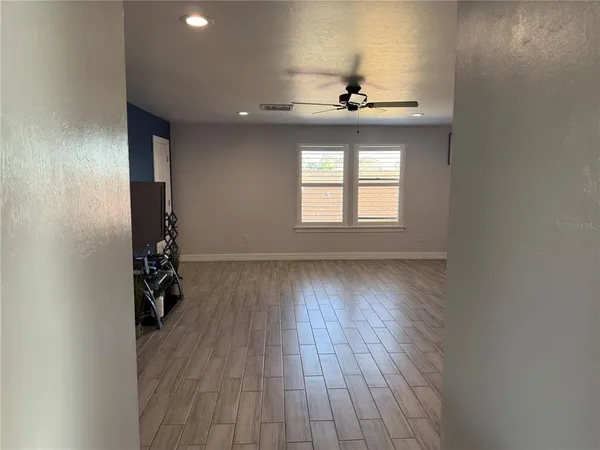 a view of an empty room with wooden floor and a window