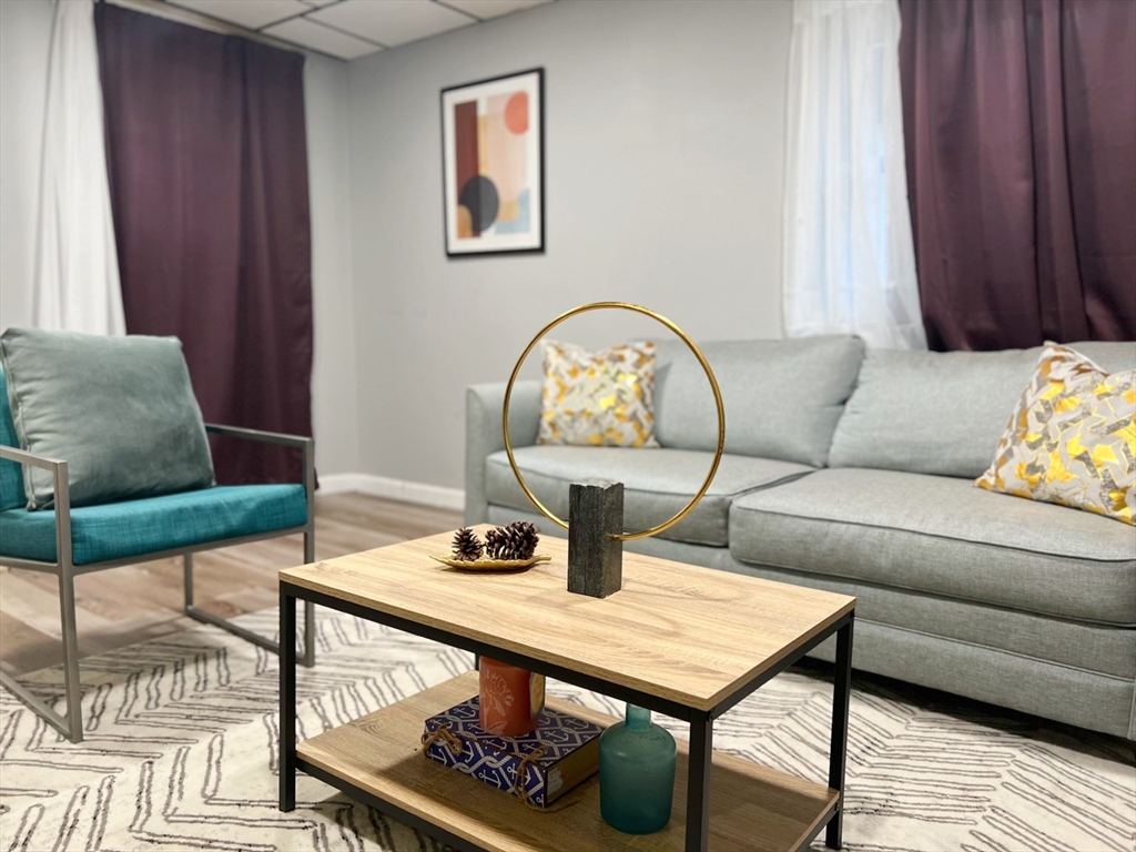 904 Main, Unit A Winchester, MA 01890 - Photo 1 of 6 a living room with furniture a rug and a window