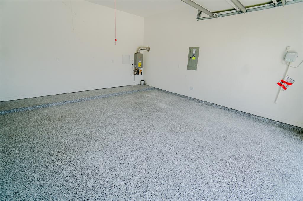1309 Old Rocksprings Pass Mansfield, TX 76063 - Photo 28 of 36 Garage interior featuring a speckled epoxy floor coating, painted white walls, and exposed ceiling joists