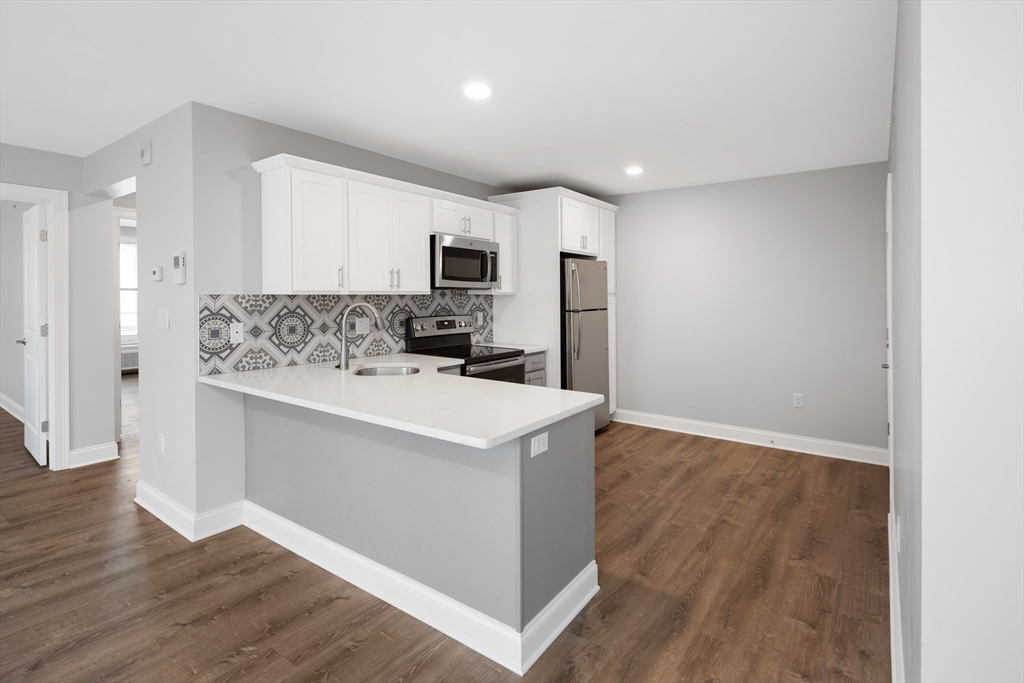 101 California Avenue, Unit 303 Quincy, MA 02169 - Photo 3 of 13 a kitchen with kitchen island a white counter top space cabinets and stainless steel appliances