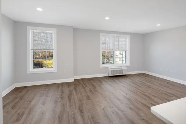 an empty room with wooden floor and windows