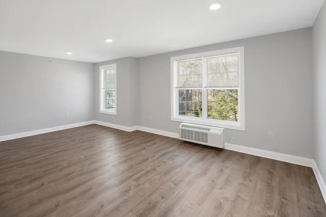 an empty room with wooden floor and windows