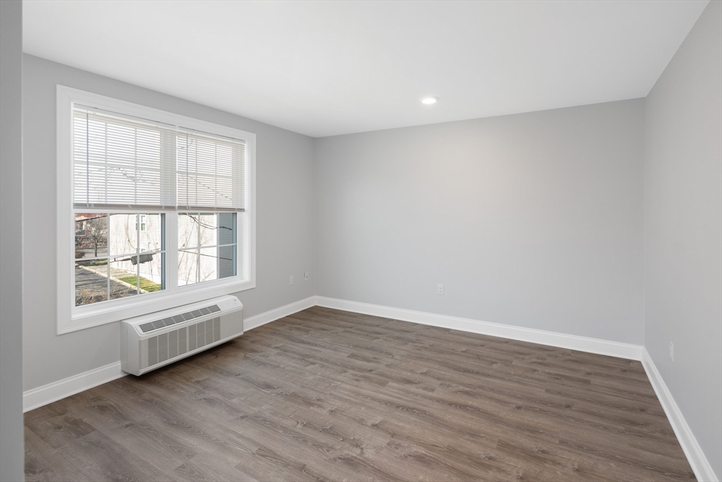 101 California Avenue, Unit 303 Quincy, MA 02169 - Photo 10 of 13 an empty room with wooden floor and windows
