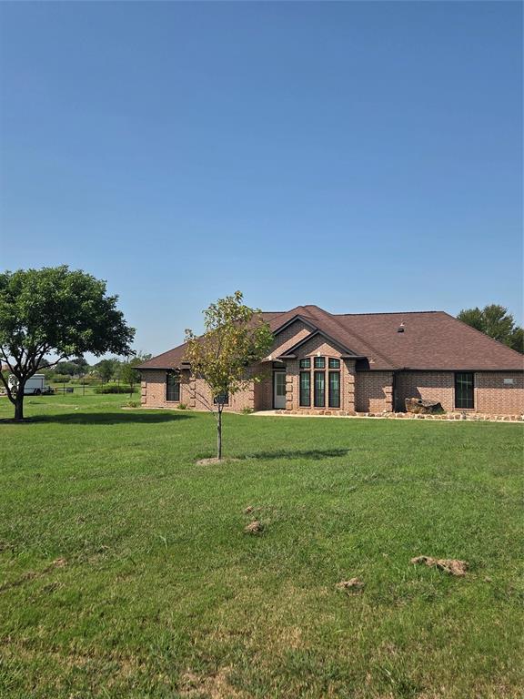 Back of property featuring a yard and brick siding