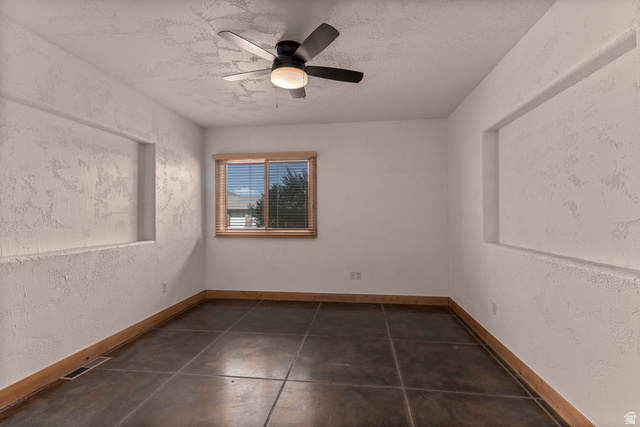 2464 East Granite Way St. George, UT 84790 - Photo 104 of 106 Empty third bedroom with a textured wall, a ceiling fan, and dark tile patterned flooring