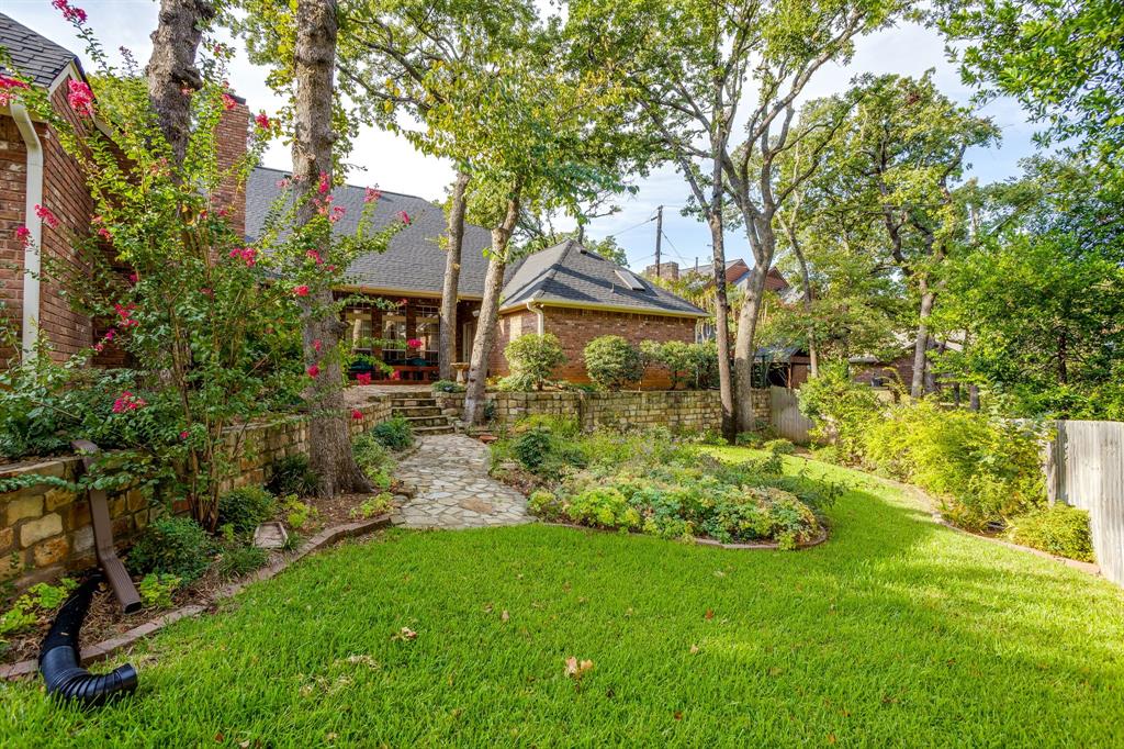 3068 High Ridge Drive Grapevine, TX 76051 - Photo 36 of 40 Expansive backyard with a stone-paved pathway, mature trees, and layered landscaping