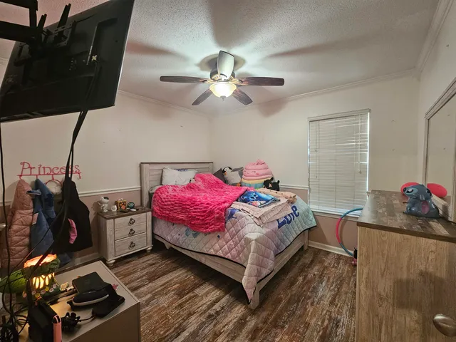 a bedroom with a bed dresser and a chandelier