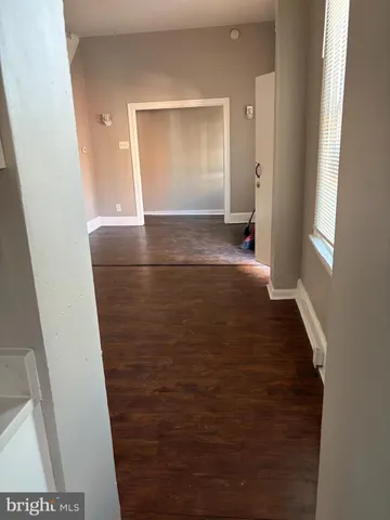 a view of hallway with window and wooden floor