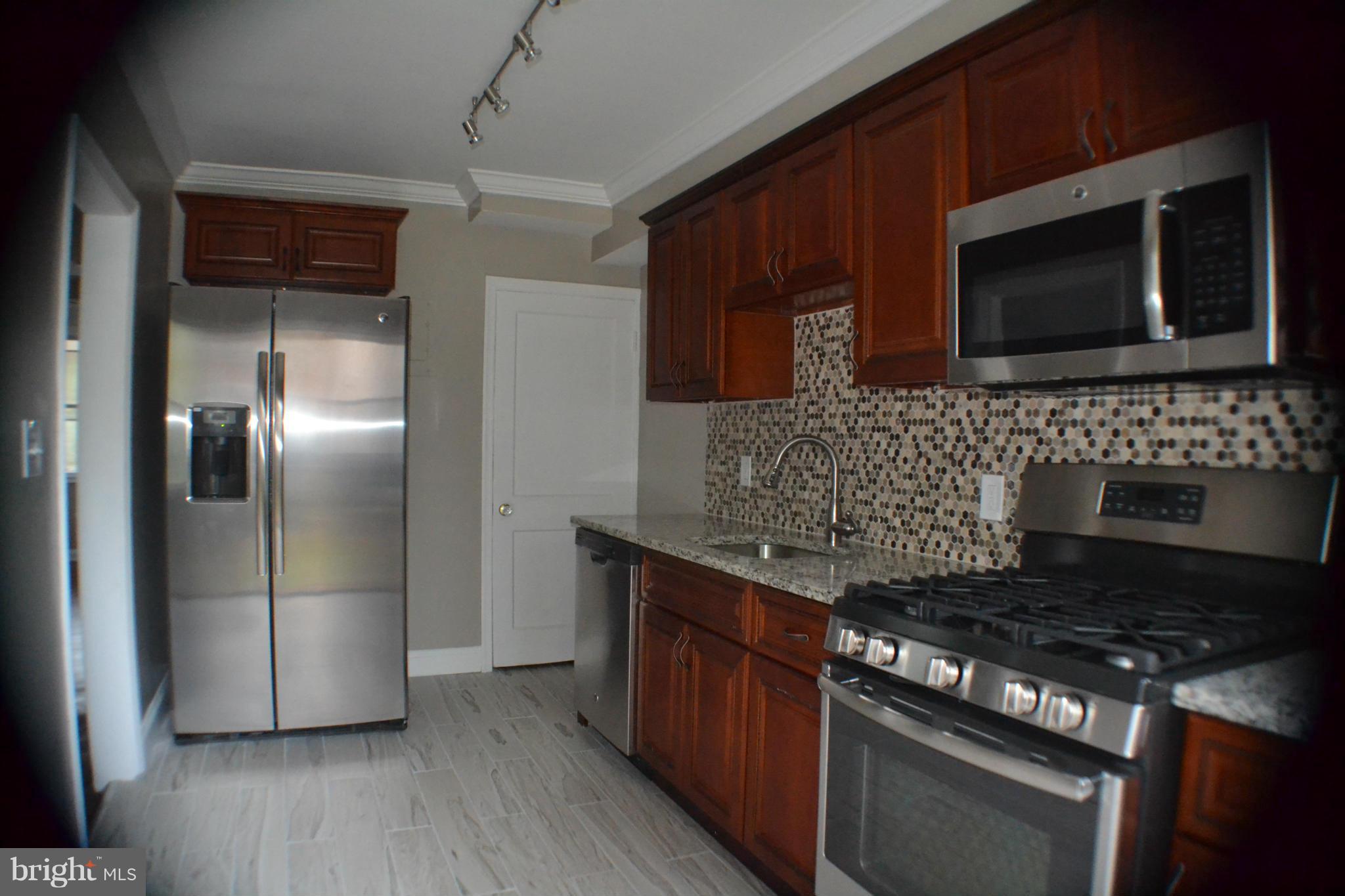 1424 Cedarcroft Road Baltimore, MD 21239 - Photo 4 of 16 a kitchen with stainless steel appliances granite countertop a stove a microwave and a refrigerator