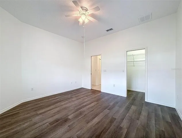 an empty room with wooden floor and fan