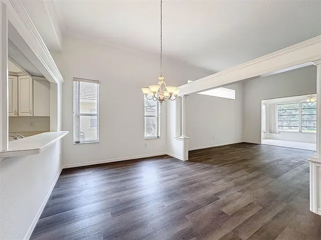 a view of an empty room with window and wooden floor