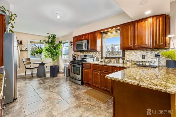 a kitchen with stainless steel appliances granite countertop a stove a sink dishwasher and a microwave oven with cabinets