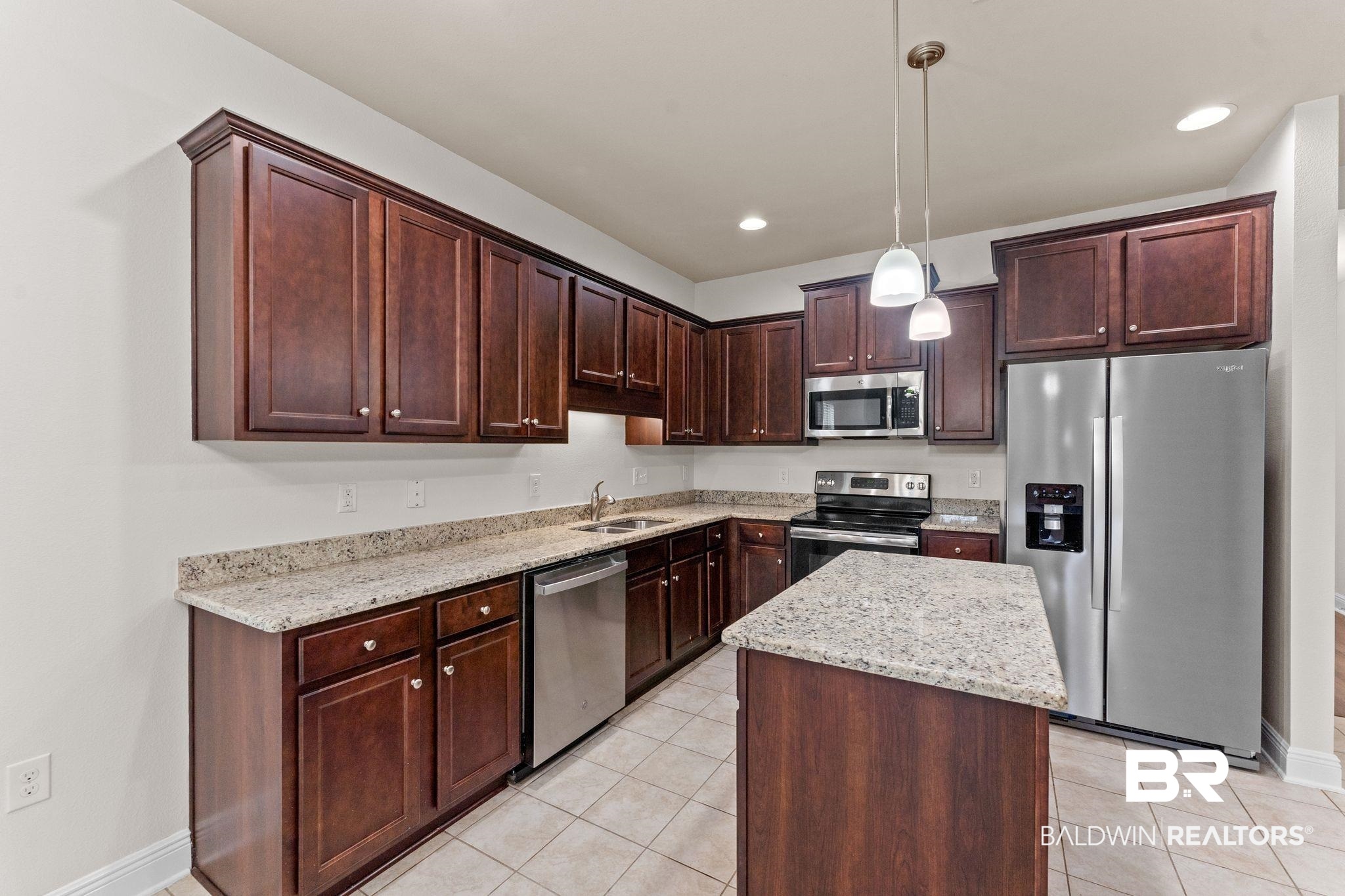 1464 Surrey Loop Foley, AL 36535 - Photo 11 of 24 Kitchen featuring stainless steel appliances, light tile patterned flooring, light stone counters, a center island, and pendant lighting
