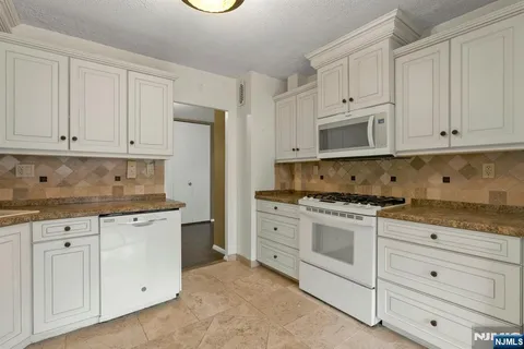 a kitchen with granite countertop white cabinets and stainless steel appliances