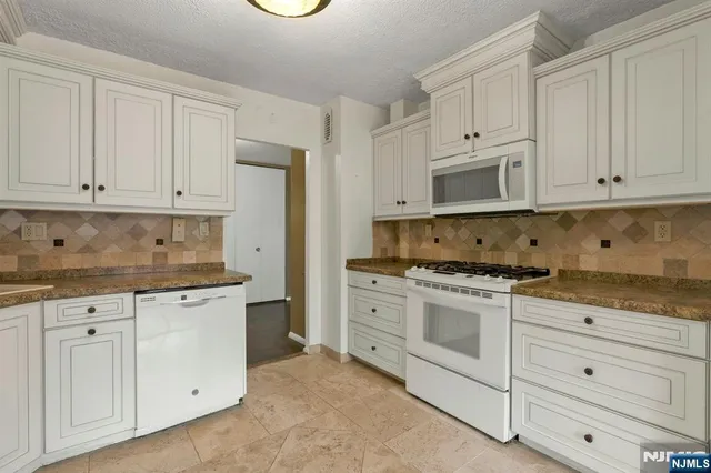 a kitchen with granite countertop white cabinets and stainless steel appliances