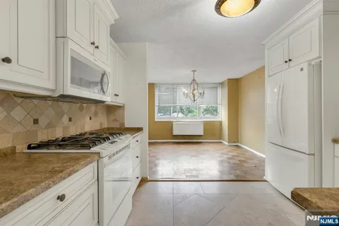 a kitchen with stainless steel appliances granite countertop a refrigerator a stove and a sink