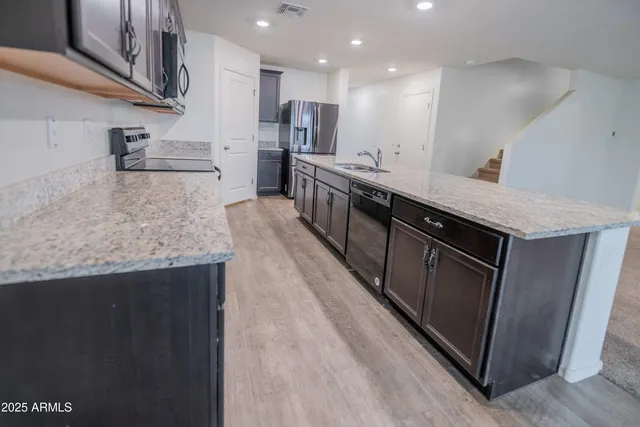 a kitchen with stainless steel appliances granite countertop a sink a stove and a wooden floors