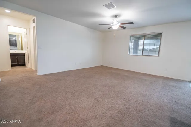 an empty room with a chandelier fan and windows