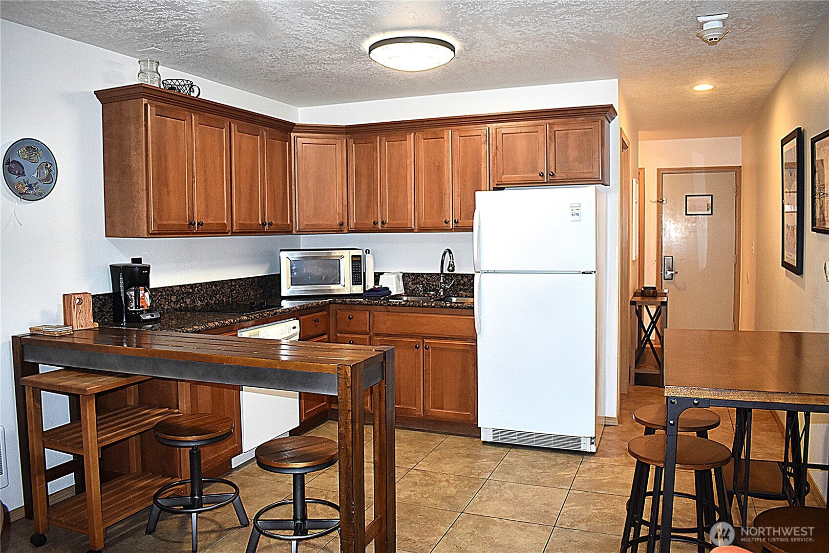 304 14th Street Northwest, Unit 115 Long Beach, WA 98631 - Photo 3 of 10 a kitchen with a refrigerator a stove a sink and chairs