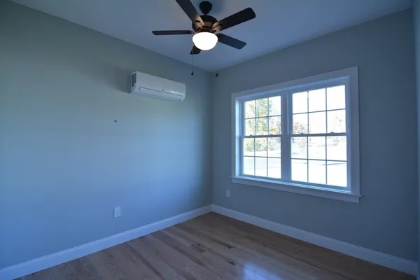 an empty room with wooden floor ceiling fan and windows