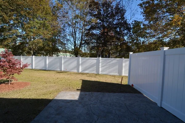 a view of a white house next to a yard and large trees