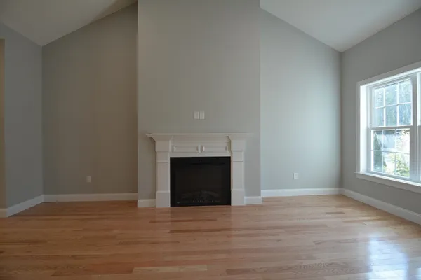 a view of empty room with wooden floor and fireplace