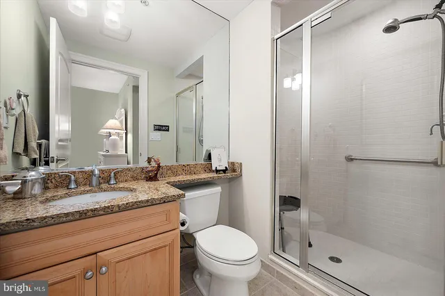 a bathroom with a granite countertop sink mirror vanity and toilet