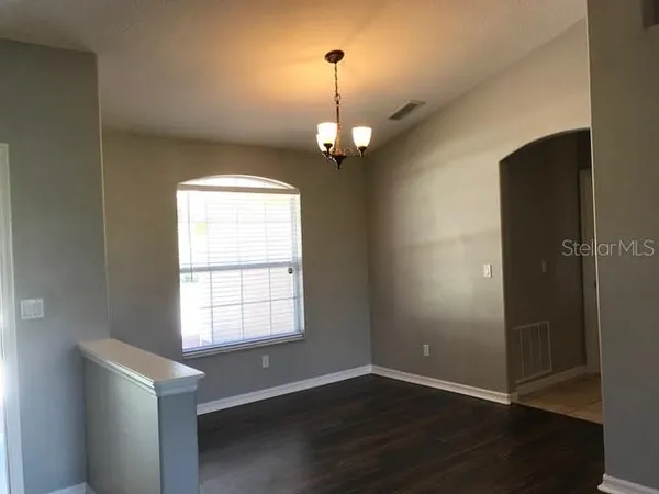 an empty room with wooden floor cabinet and windows
