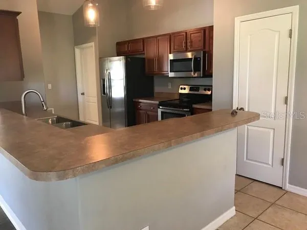 a kitchen with stainless steel appliances granite countertop a sink a stove and a refrigerator with wooden floor