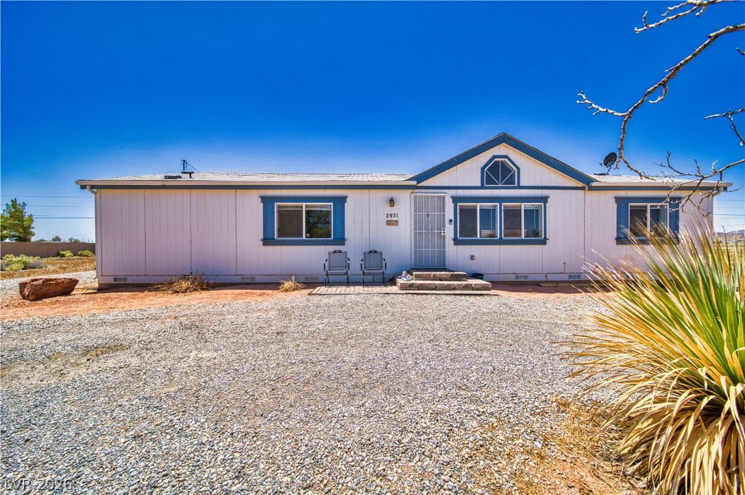2931 Rio Rancho Drive, Unit 4 Pahrump, NV 89048 - Photo 2 of 21 A modest desert residence, featuring a gravel driveway and simple landscaping under a clear sky.