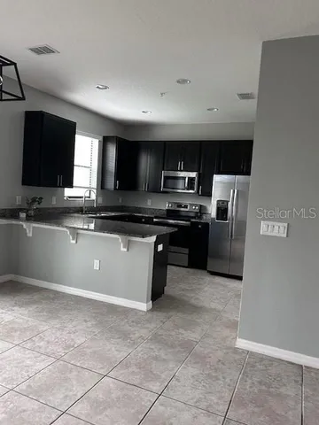 a kitchen with stainless steel appliances granite countertop a stove top oven a sink a microwave and a refrigerator