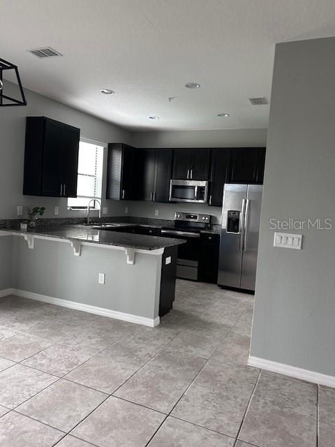 2406 Seven Oaks Drive St. Cloud, FL 34772 - Photo 5 of 11 a kitchen with stainless steel appliances granite countertop a stove top oven a sink a microwave and a refrigerator