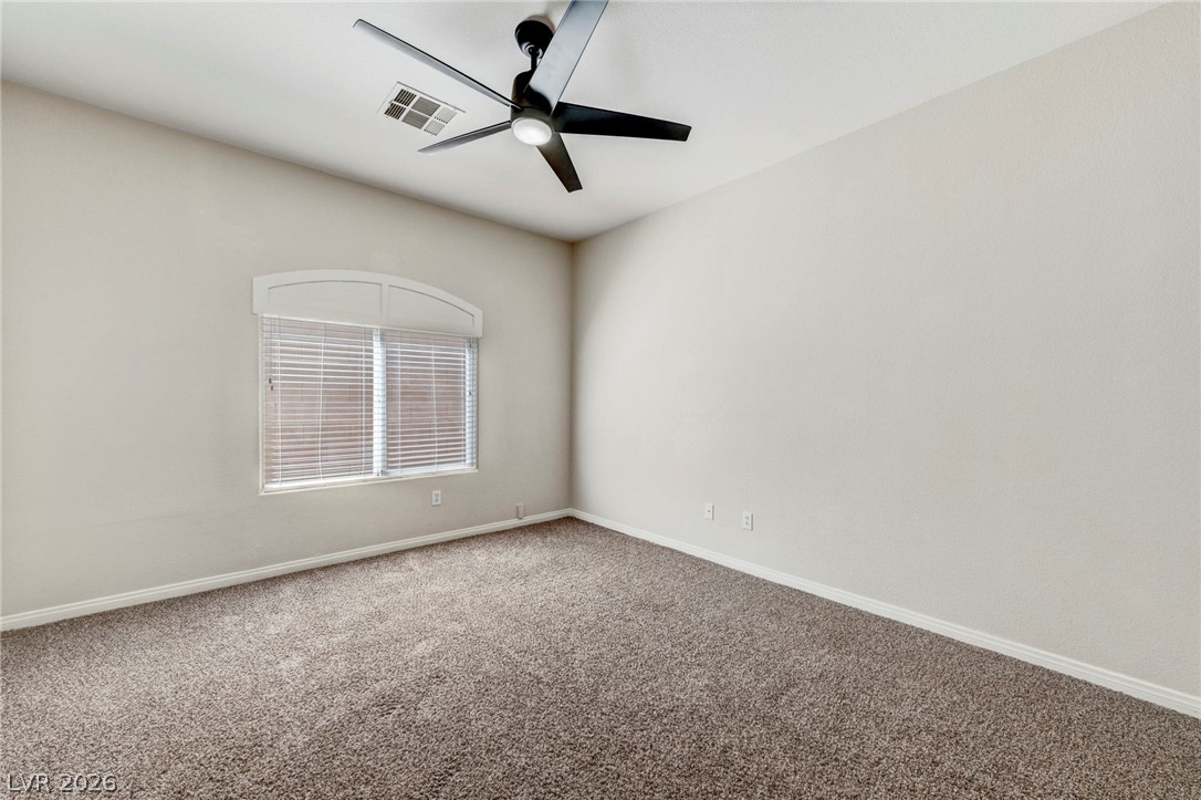 740 Aldo Rae Court, Unit NONE Henderson, NV 89052 - Photo 18 of 35 A spacious, neutral-toned room features soft carpet and a wide window for natural illumination.