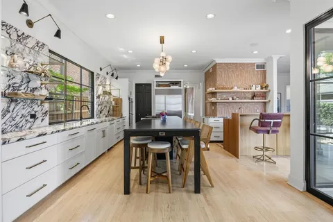 a kitchen with stainless steel appliances kitchen island granite countertop a table chairs sink and cabinets